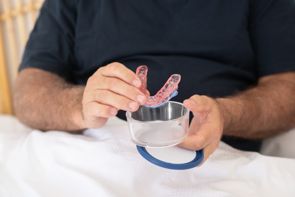 Male patient holding SomnoDent Avant wtih container 1