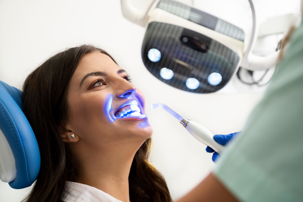 Teeth whitening procedure. Dentist using light on patient's teeth. How long does teeth whitening take for best results? Dental care.